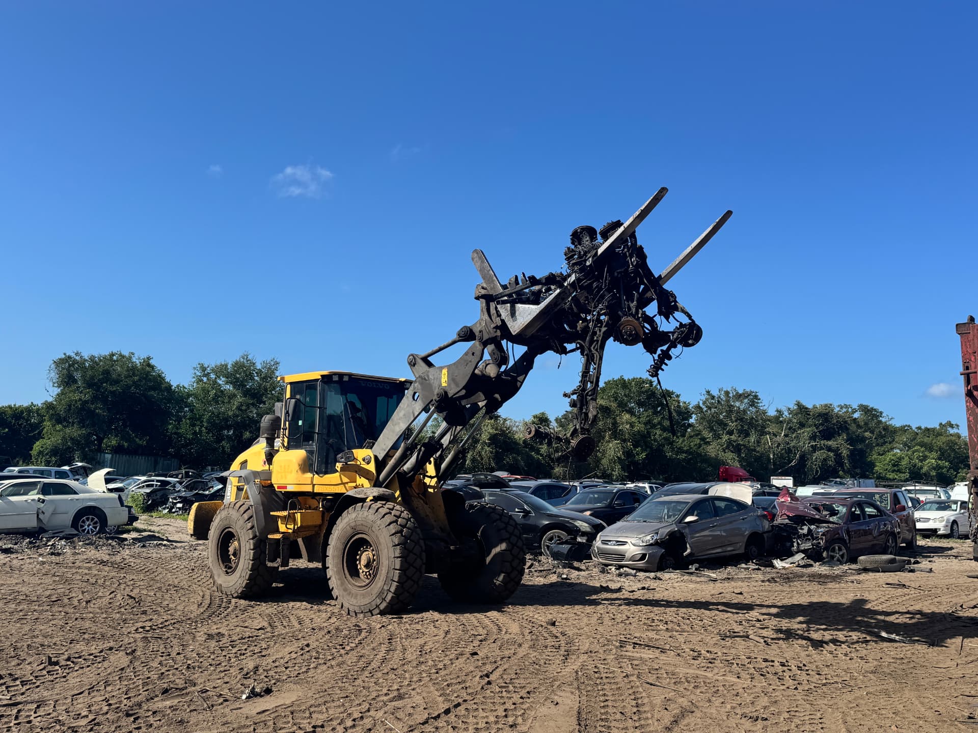 Yellow loader moving crushed vehicles in the scrapyard