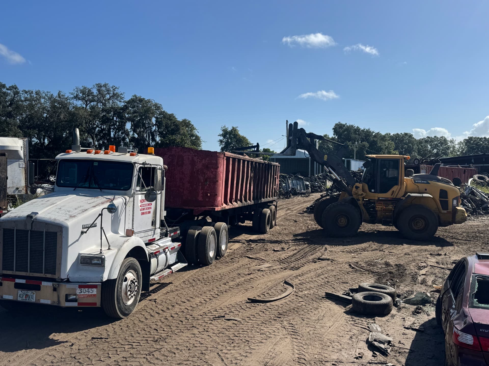 White Kenworth truck with red roll-off dumpster
